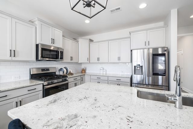 Bright and modern kitchen with white cabinets and stainless steel appliances, featuring a granite countertop island.